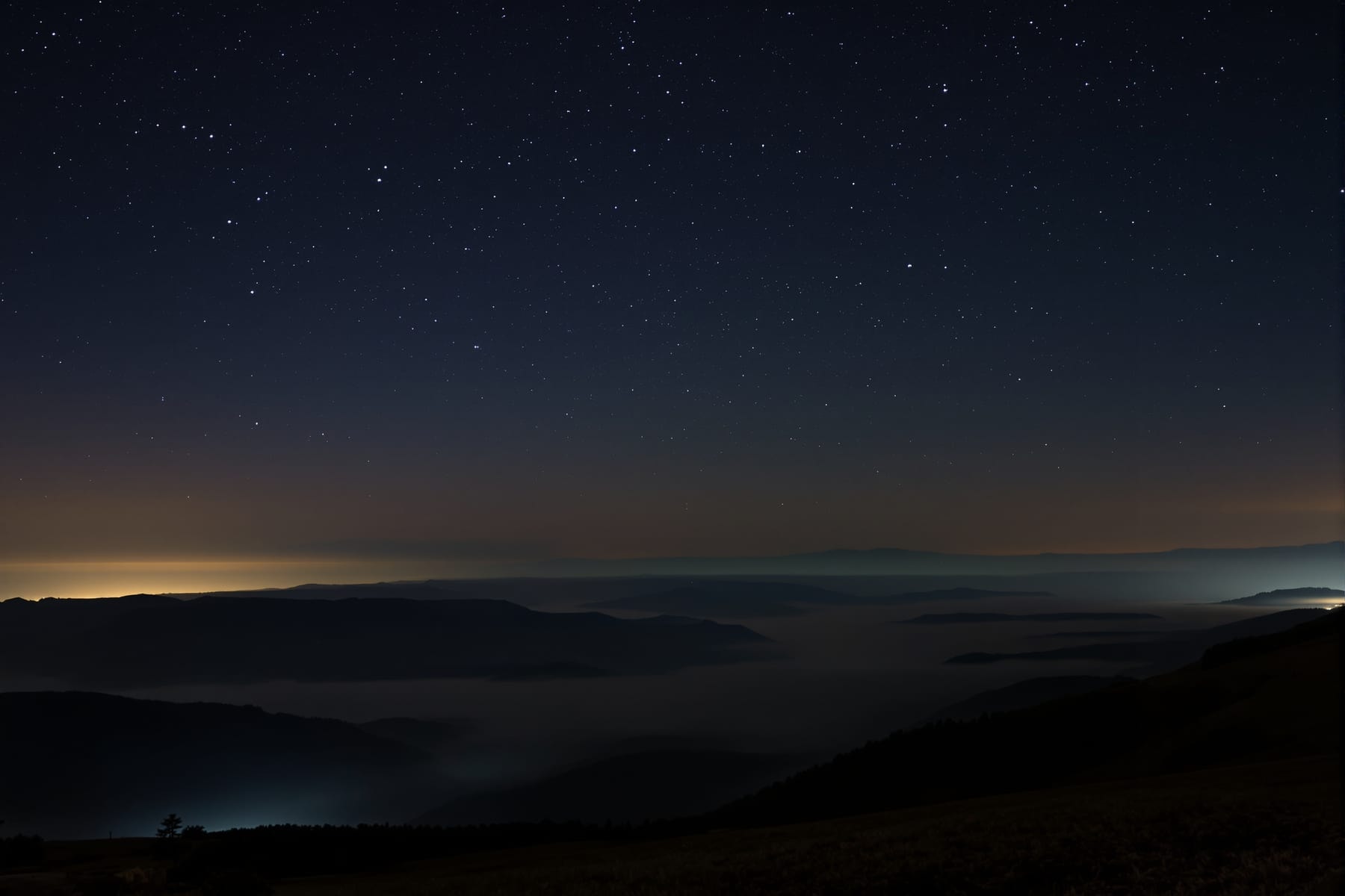 Looking north from an elevated viewpoint over a misty valley toward a faint auroral glow