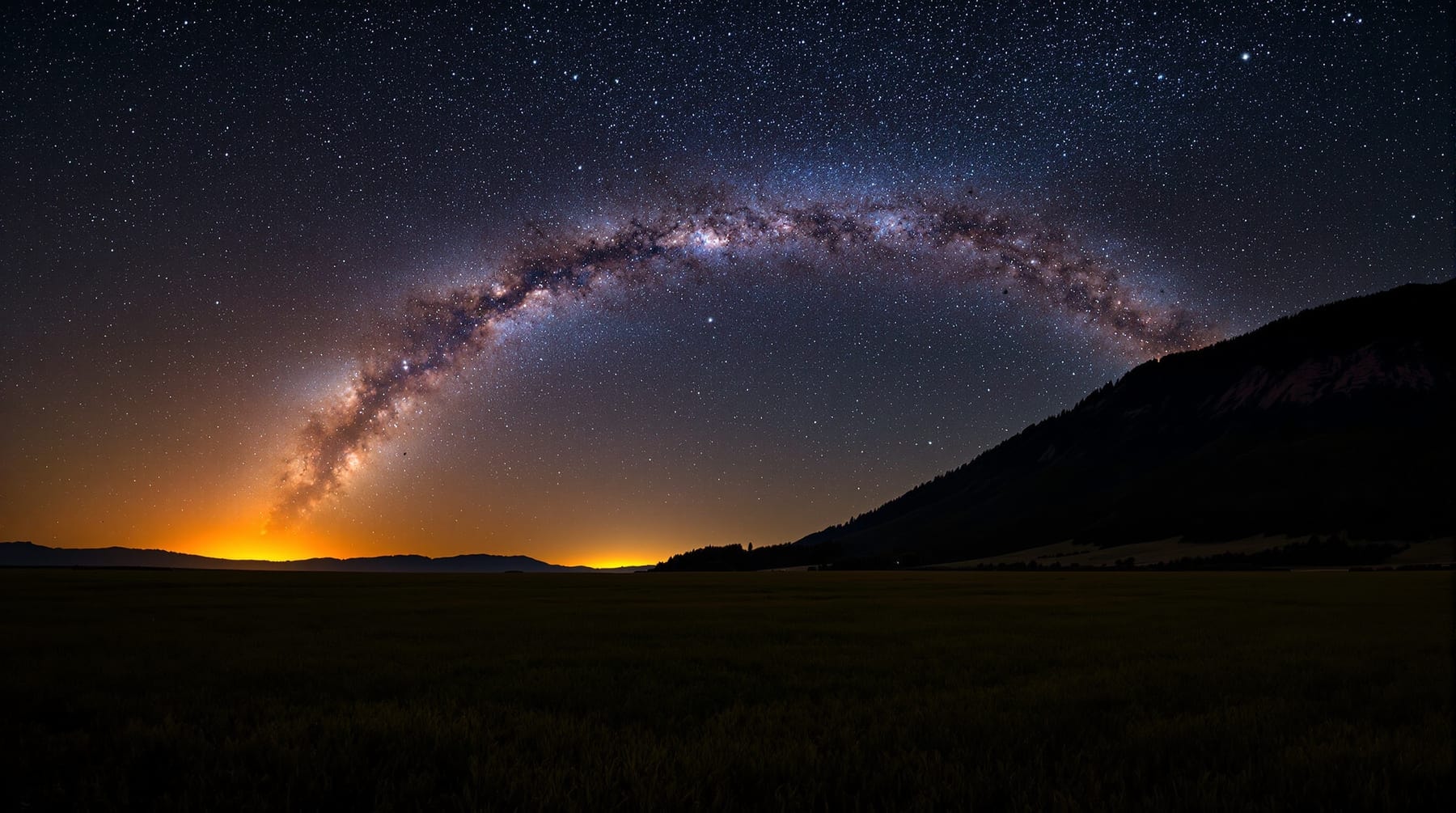 The summer Milky Way over farmland and a forested ridge in the Fraser Valley